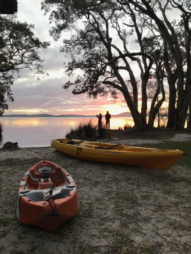 Red and yellow kayaks on the beach at Mungo Brush at sunset.