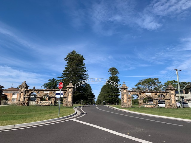 Historic Tanilba Bay Water Gate with norfolk pines lining the road behind with clear blue sky