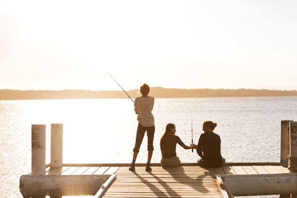 Friends fishing at Cams Wharf in Lake Macquarie, NSW as the sun sets
