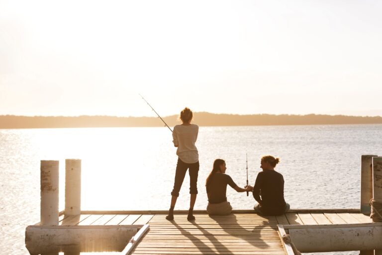 Friends fishing at Cams Wharf in Lake Macquarie, NSW as the sun sets