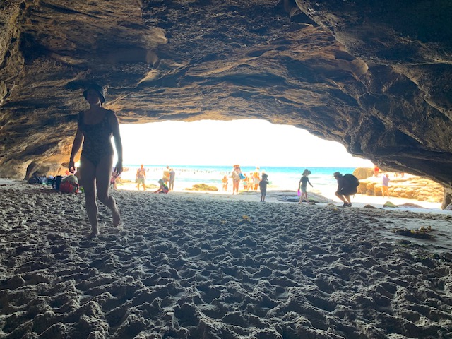 People enjoying a picnic in the huge walk-through cave at Caves Beach