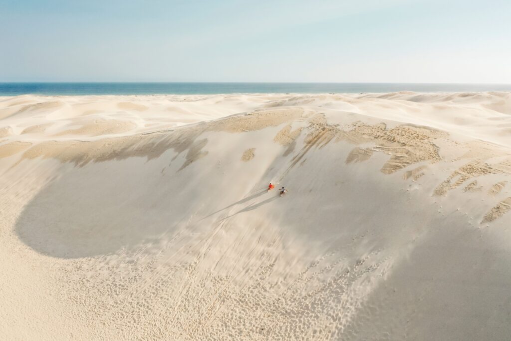 A couple sandboarding down a huge sand dune on Stockton Sand Dunes
