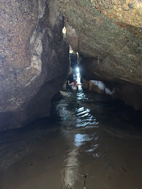 A woman exploring a flooded sea cave at Caves Beach
