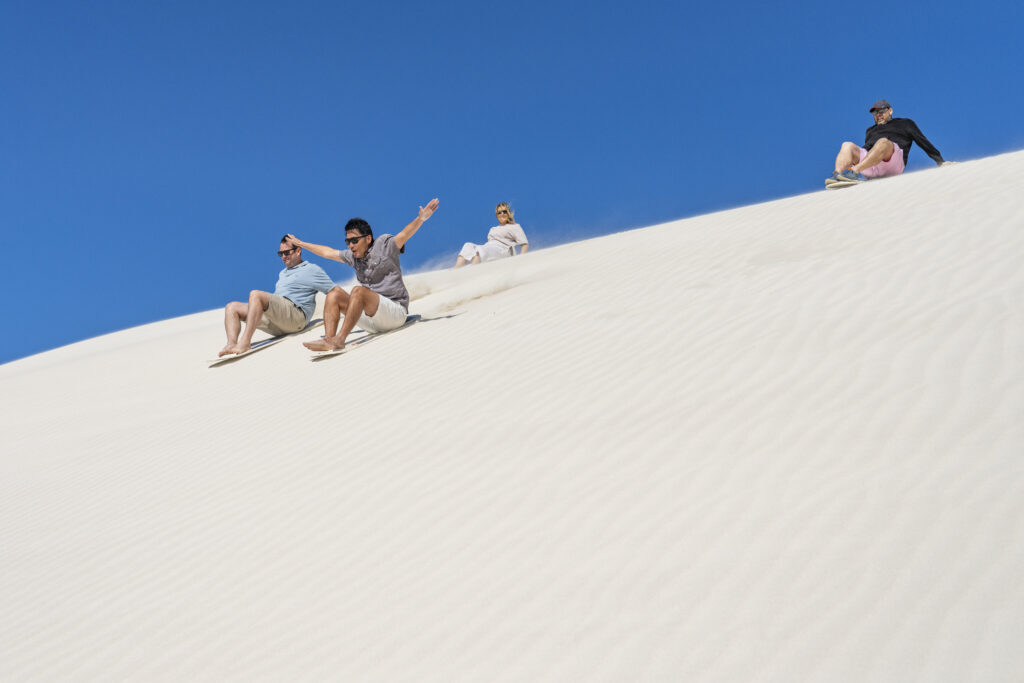 People enjoying an exhilarating sand board ride down the sand dunes at Lancelin, Western Australia