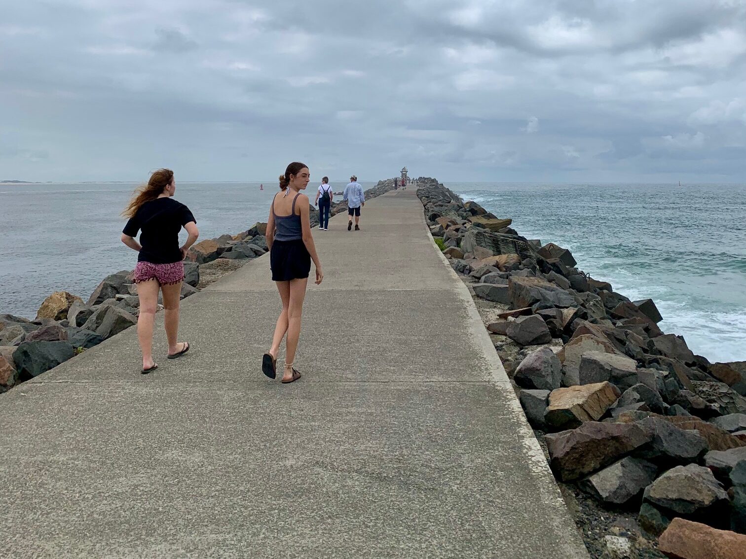 2 girls walking along Nobbys break wall looking for coal ships