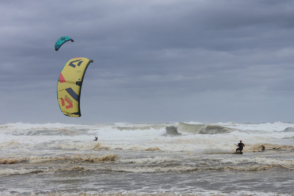 Kitesurfers play in the waves on Birubi Beach on a stormy day.