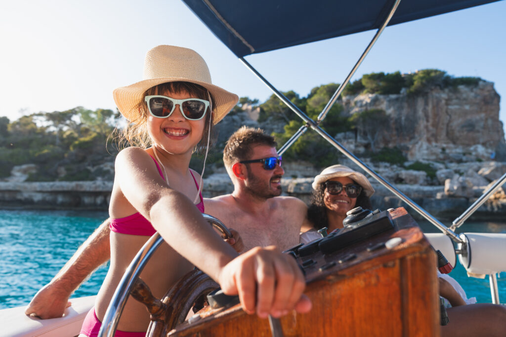 Young girl enjoying driving the boat whilst avoiding seasickness