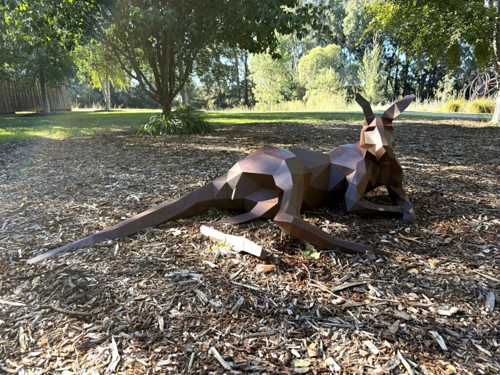 Sculpture of kangaroo lying down in the shade of eucalyptus trees on the banks of the Gudgegon River, Mudgee