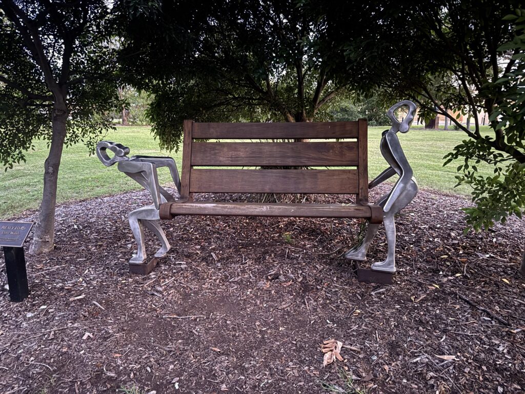 A sculpture showing two figures carrying the park bench on the Mudgee Sculpture Walk.