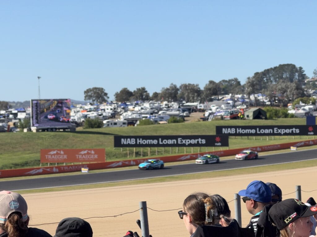 Crowd watching the cars racing down Conrod Straight overlooking the campgrounds and keeping updated by the big screen