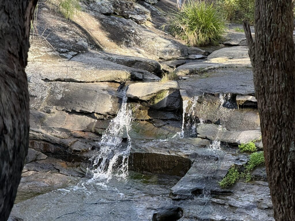 Small waterfalls cascading over a wide rock creek ledge