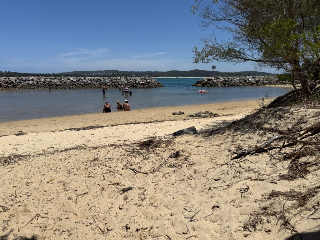 Families enjoying a summer swim in the sheltered shallow sandy water of Grannies Pool on the edge of Swansea Channel in Lake Macquarie