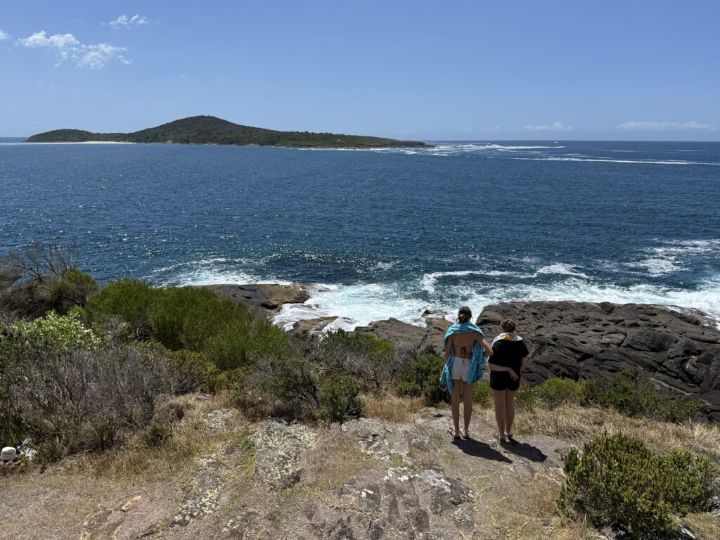2 girls admiring the view over Fingal Bay towards Fingal Island on a clear summer day from Barry Lookout