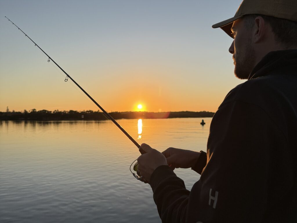Silhouette of man fishing at sunrise in Port Stephens