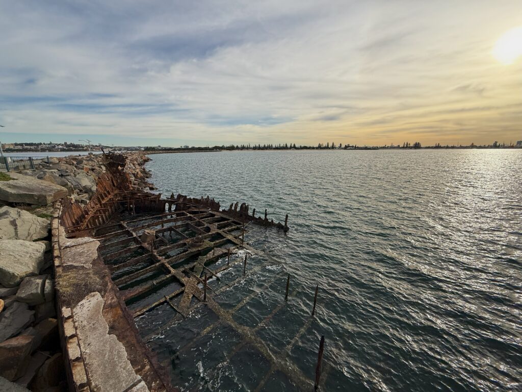 The rusting relic of the Adolphe resting against the Stockton Breakwall as part of the Shipwreck Walk at sunset. A testament to the dangers faced by mariners in early days.
