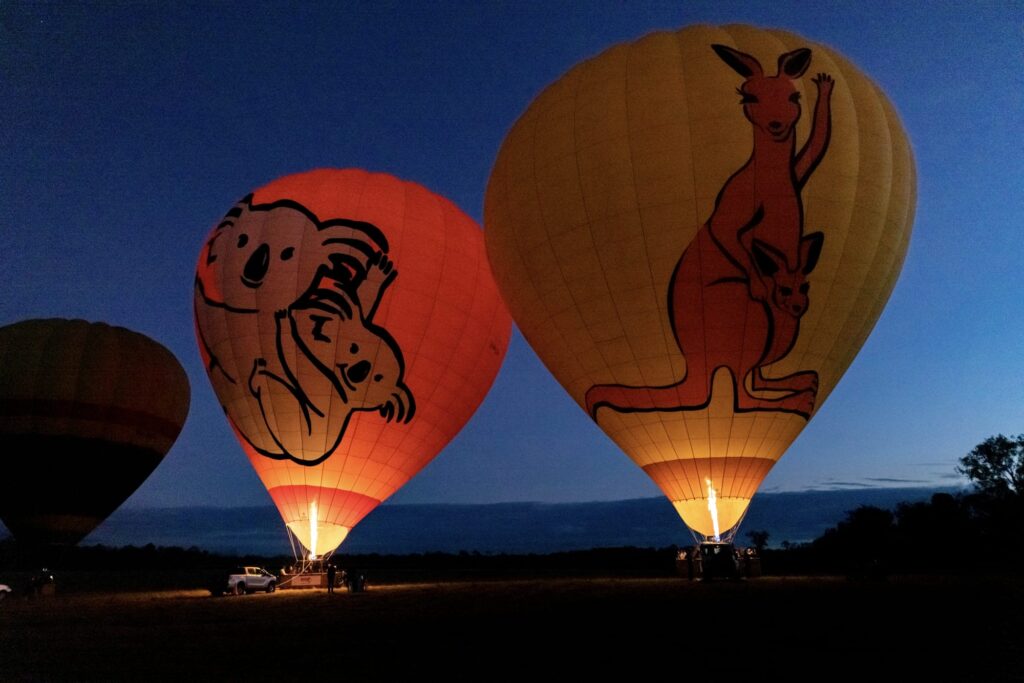 Hot air balloons heat up at sunrise before rising to float over the Atherton Tablelands.