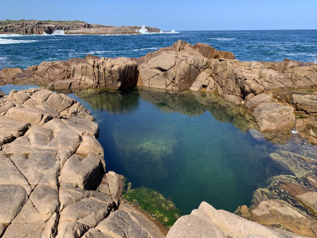 The Champagne Pool at Boat Harbour is a still emerald green on a calm day at low tide.