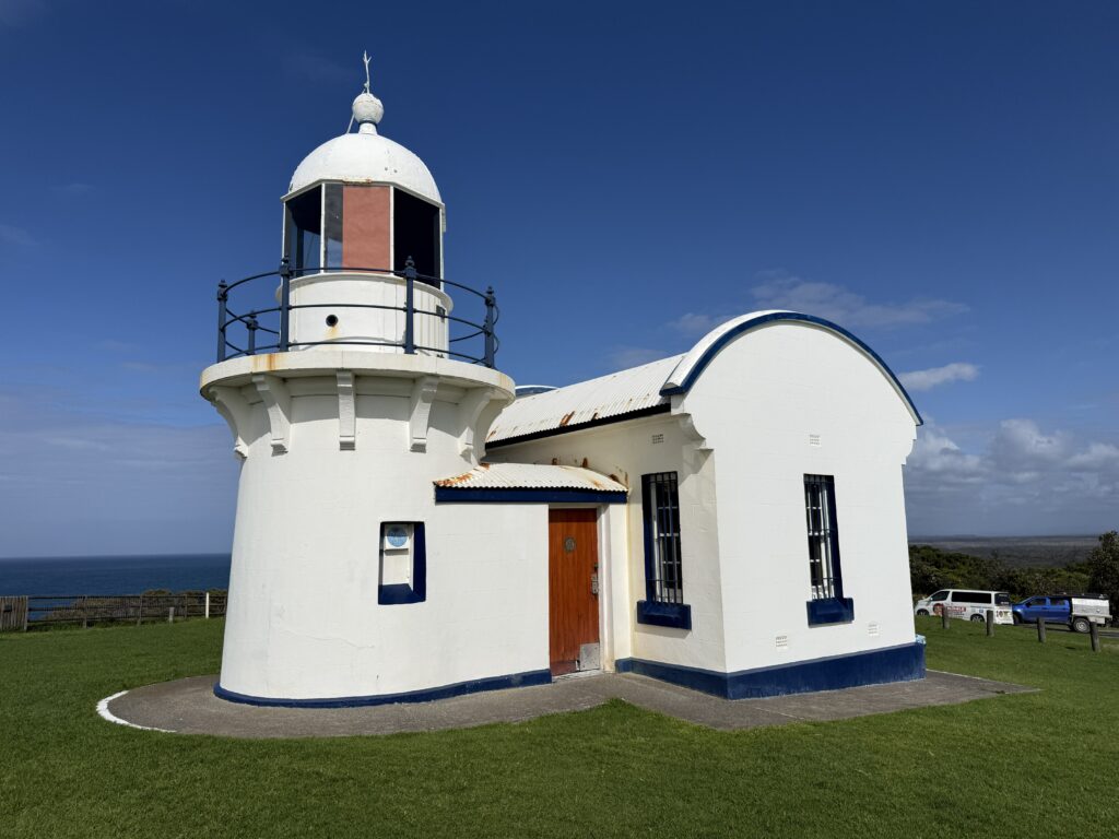 The small white lighthouse with red doors protects mariners at Crowdy Head.
