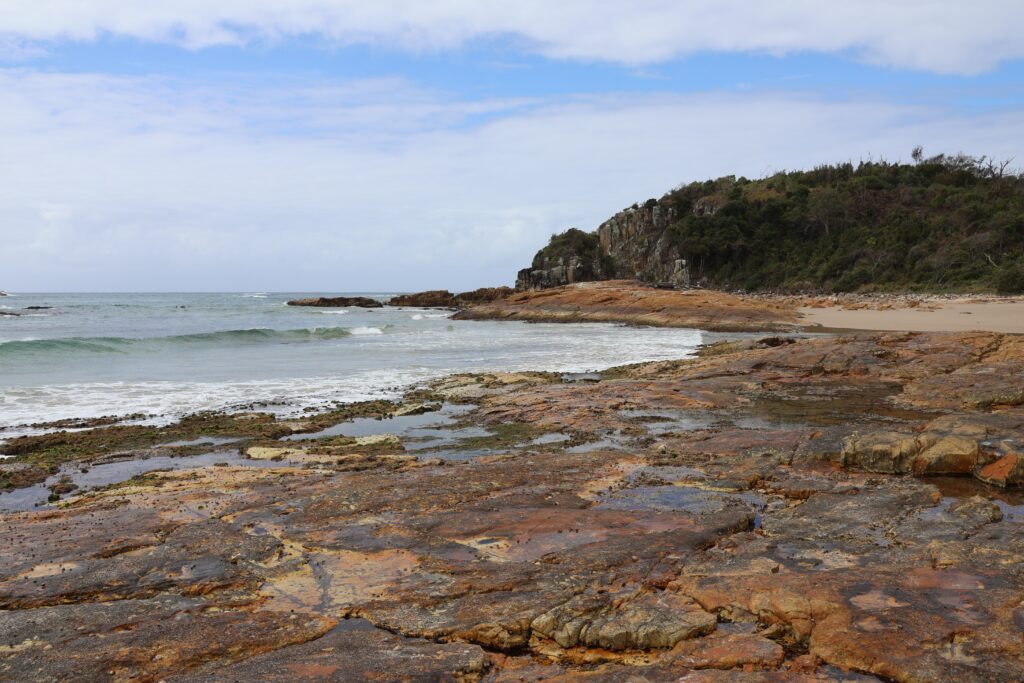 Orange rocks form rockpools at low tide at Diamond Head