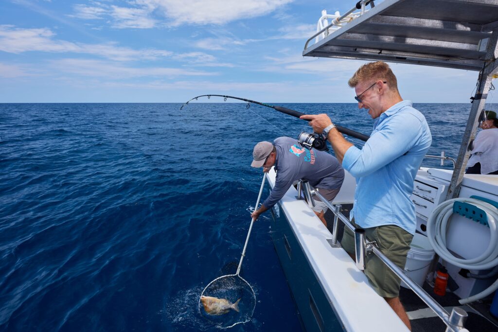 A man catches a fish on a fishing charter on the great barrier reef in Far North Queensland