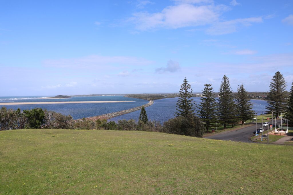 View from Pilot Hill Lookout towards Manning Point overlooks norfolk pines lining the grassy park, Harrington Breakwall and the Manning River.