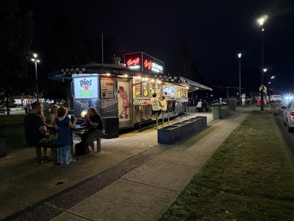 People seated at the iconic Harry's Cafe de Wheels eating its famous pies with peas and gravy along the Newcastle Harbour Foreshore Walk