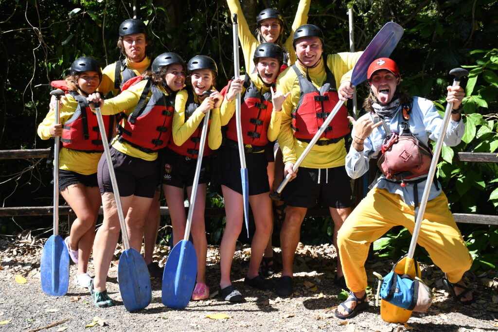My family with all our safety equipment including helmets, life jackets, self draining shoes, yellow long sleeved shirts and our blue paddles before starting the rafting trip
