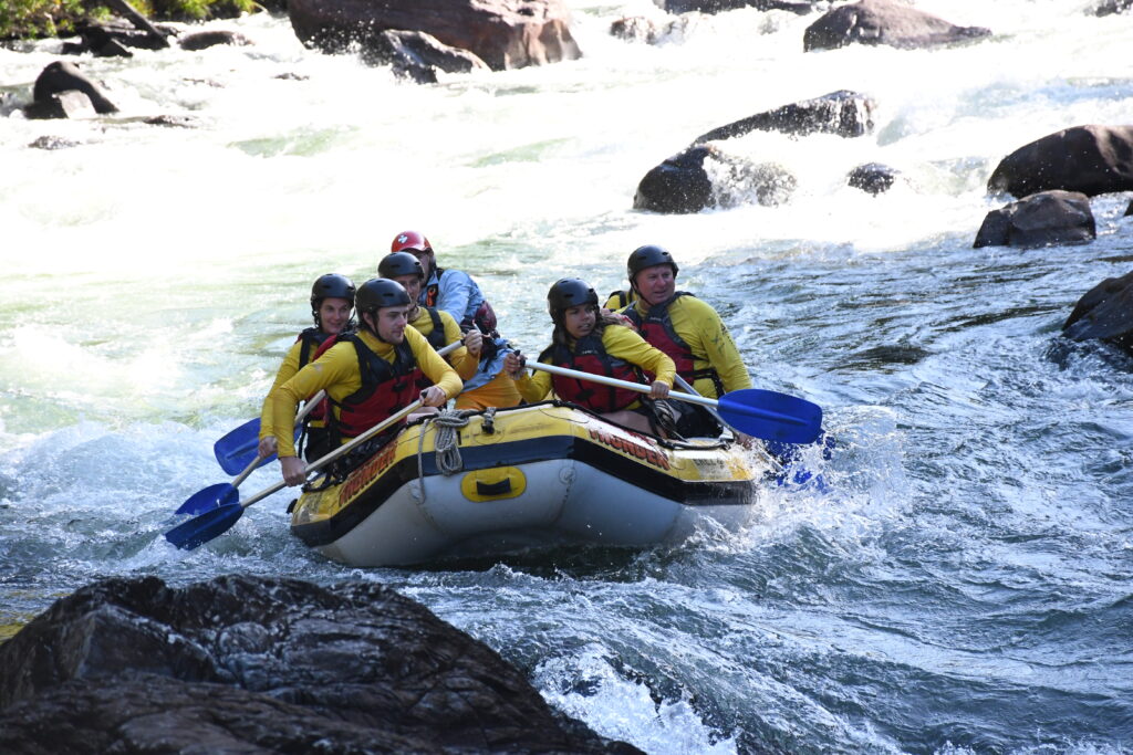 Paddling as a team in our yellow inflatable raft as we enter the first rapid on the Tully River