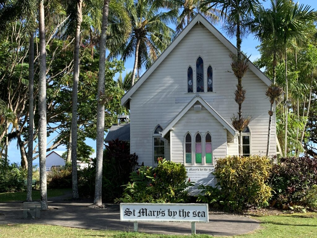 White timber St Mary's by the Sea chapel sits nestled in the palm trees in Rex Smeale Park.