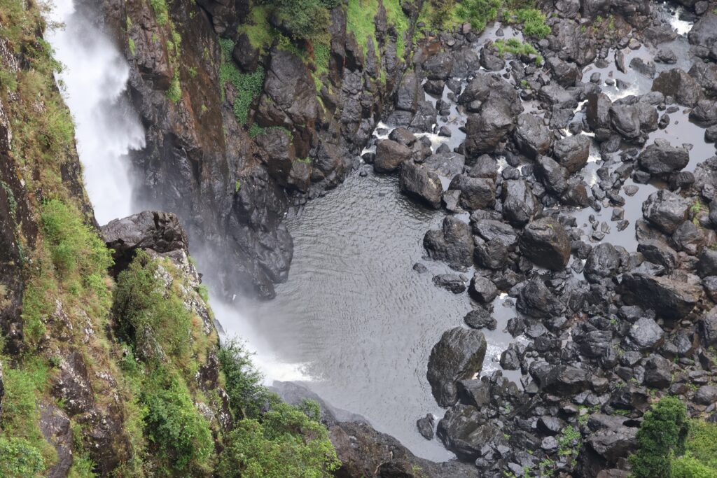 Pool at the bottom of Ellenborough falls surrounded by black boulders
