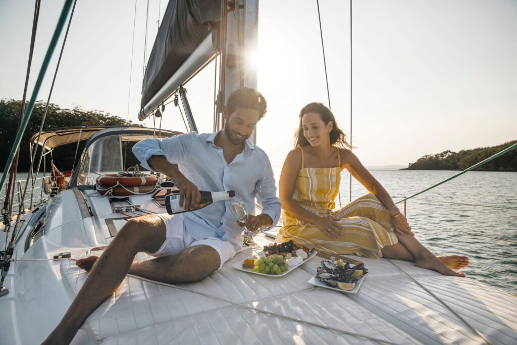 Couple enjoying an evening drink aboard a sailing boat at Fame Cove, in Port Stephens
