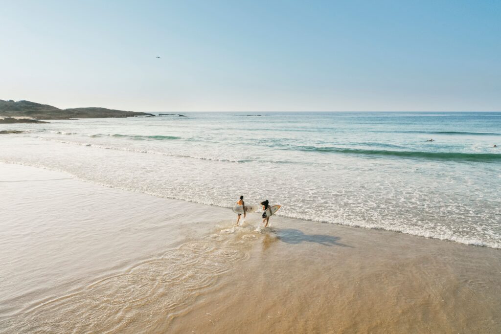 Surfers entering the water for a surf in the morning at Birubi Beach, Port Stephens